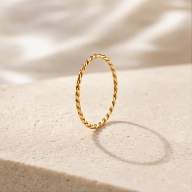 Liora, bague torsadée dorée RIVANE sur fond ivoire.